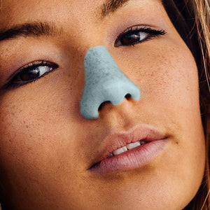 Woman with freckles and blue nose sunscreen on her face